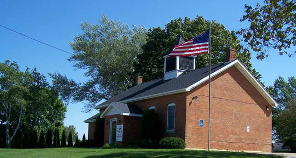 Red-brick building with American flag and accessible parking sign.