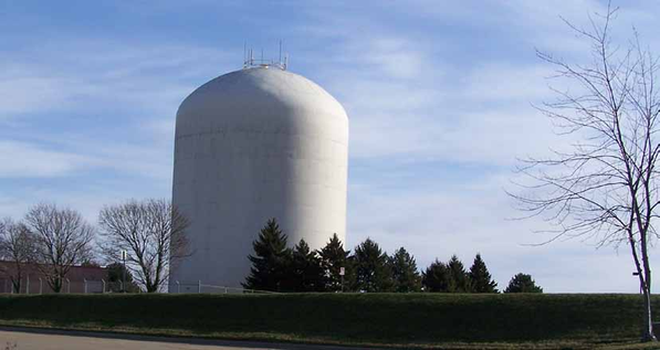 Large cylindrical water tower surrounded by trees.