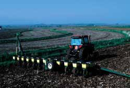 Tractor working on a large, cultivated farm field.