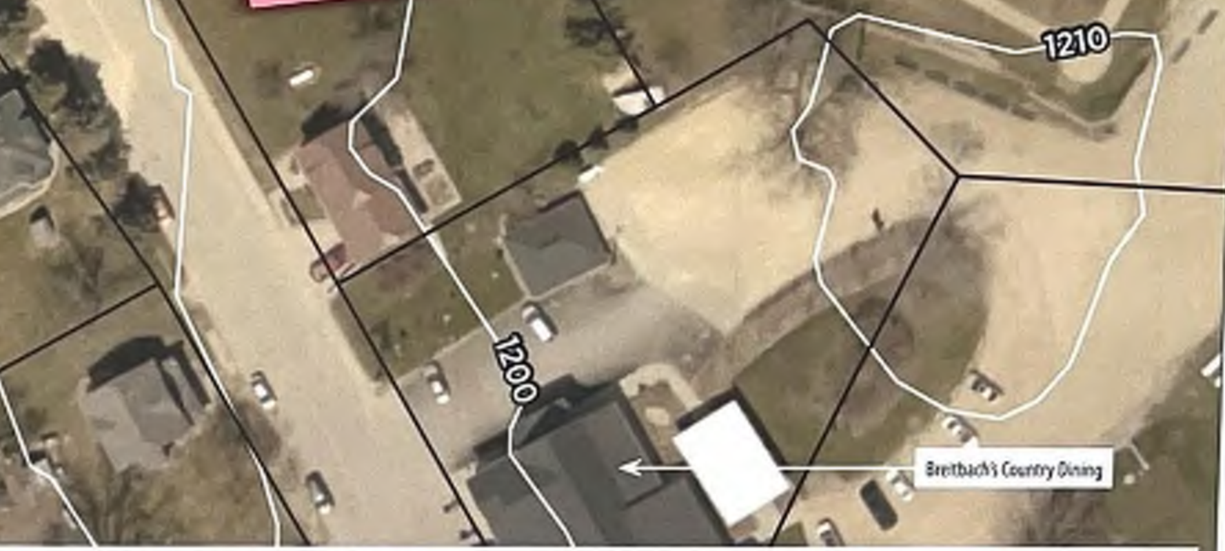 The map depicts a geographic layout featuring outlined properties and roads. It includes labeled buildings such as 'Bredtbach's Country Dining,' and other house numbers like '1200' and '1210.' The orientation and spatial relationships among the properties and streets are clearly marked, aiding the user in navigating the area.