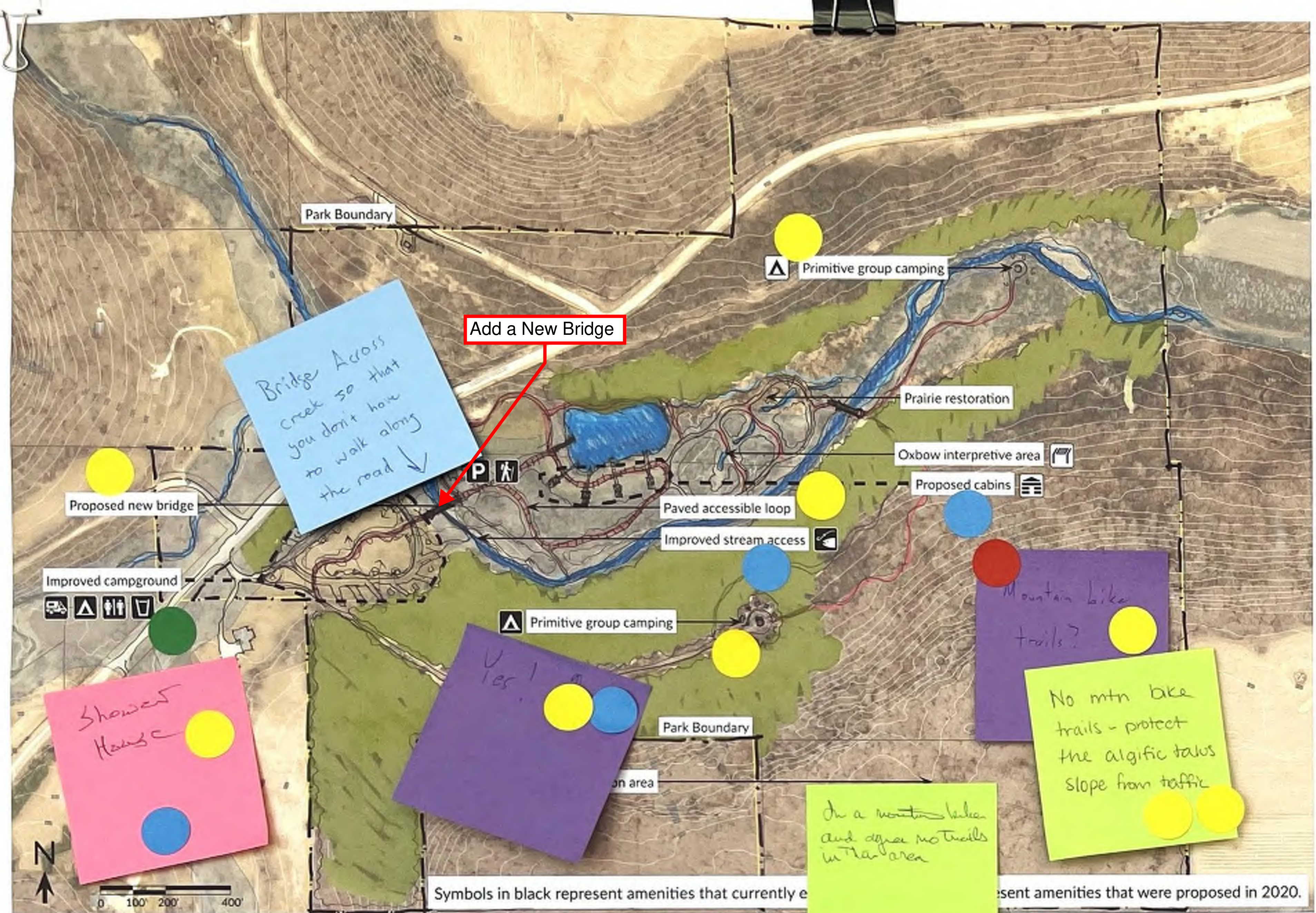 The map illustrates a designated park area featuring trails, proposed new bridge locations, camping areas, and other amenities. Comments appear on sticky notes indicating areas of interest, modifications, or suggestions, such as adding a new bridge. The boundaries, key landmarks, and spatial layout of the park are clearly marked, including paths for accessibility, primitive camping spots, and restoration areas.