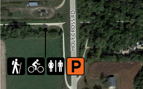 The map displays a section of land with Holy Cross Road to the right. It features a pedestrian path, a cycling path, and symbols indicating accessible areas for men, women, and a designated parking area. Spatial relationships are illustrated by the connection between pathways and parking, as well as their proximity to the road.